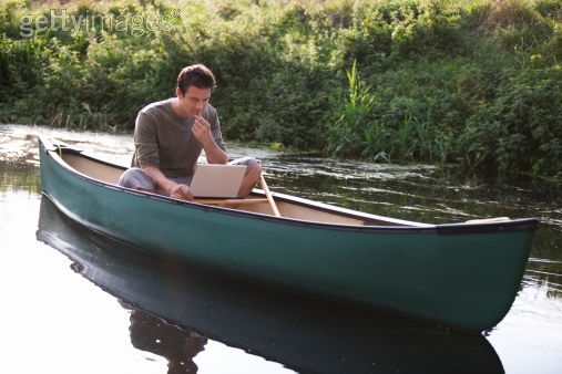 Royalty-free Image: Young man sitting in a boat working on…